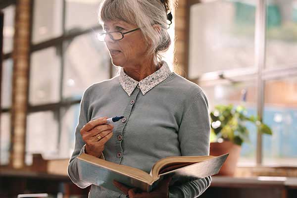Older teacher in classroom with book