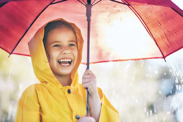 Young girl in yellow raincoat with red umbrella