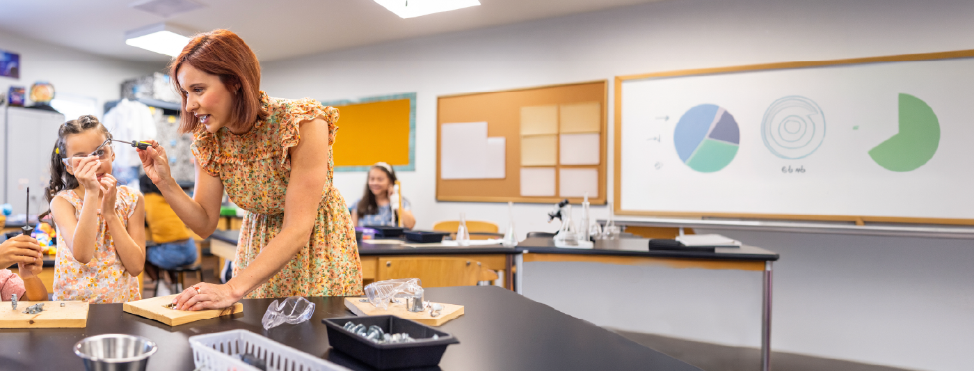 Teacher assisting students with a hands-on science experiment in a classroom.