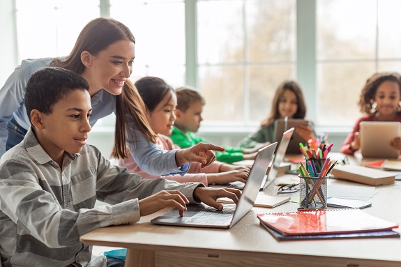 teacher assisting student with laptop