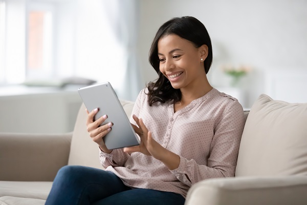 educator watching webinar on tablet sitting on couch