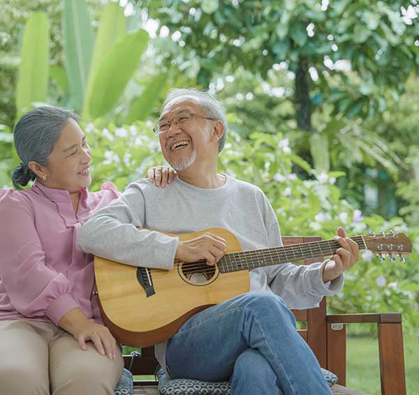 Asian couple outside with man playing guitar